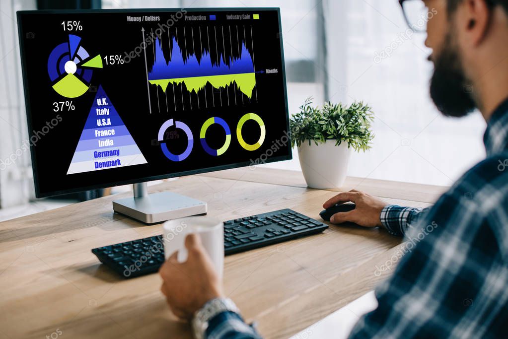 cropped shot of man with cup of coffee using computer with statistics charts on screen