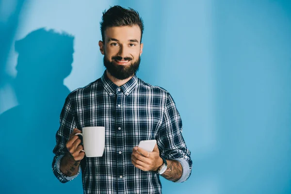 Glimlachende Man Geruite Hemd Holding Smartphone Kopje Koffie — Gratis stockfoto