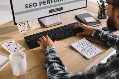seo Yöneticisi ekose gömlekli işyerinde bilgisayar kullanarak kırpılmış atış