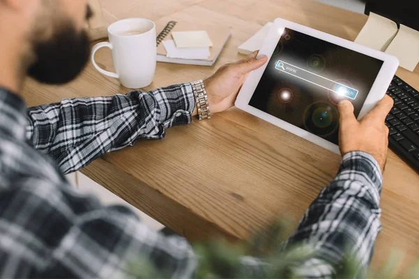 cropped shot of developer using tablet with search app at workplace