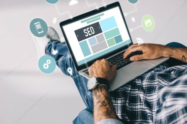 Seo simgeleri ile dizüstü bilgisayar üzerinde çalışan dövmeli geliştirici görünümünü kırpılmış