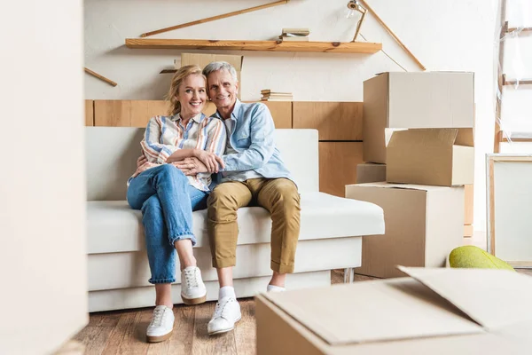 Feliz Pareja Ancianos Abrazando Sonriendo Cámara Mientras Sientan Juntos Sofá — Foto de Stock