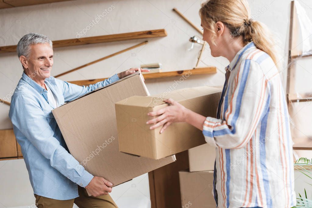 happy elderly couple holding cardboard boxes during relocation
