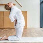 Vista lateral de mujer madura deportiva practicando yoga en estera de yoga