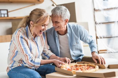 Pizza yemek ve yeni evinde gülen mutlu üst düzey çift