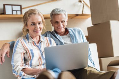 happy senior couple using laptop together during relocation clipart