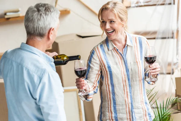 Homem Sênior Derramando Vinho Para Esposa Feliz Mudar Nova Casa — Fotografia de Stock