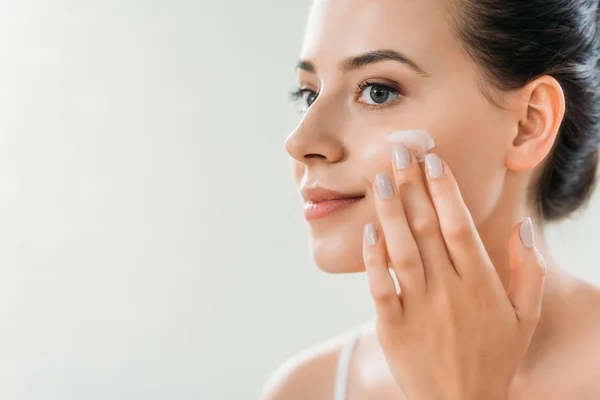 Bela Sorrindo Jovem Mulher Aplicando Creme Facial Olhando Para Longe — Fotografia de Stock