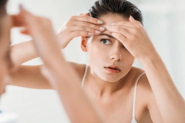 Genç kadının üzerinde deri alın ve banyo aynaya bakarak kontrol seçici odak  
