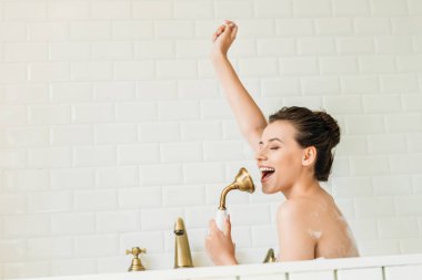 beautiful happy girl singing and having fun in bathtub clipart