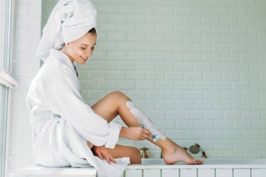 güzel genç kadın Tıraş bacak banyo traş makinesi ile gülümseyen 
