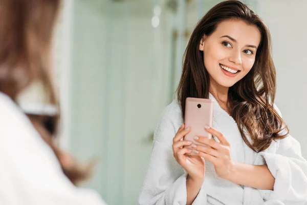 Sonriente Mujer Joven Albornoz Tomando Selfie Con Teléfono Inteligente Espejo — Foto de Stock