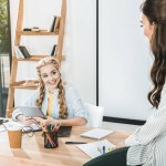 Young multicultural businesswomen having conversation at workplace in office