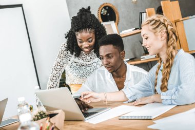 çok kültürlü gülümseyen işadamı ve işyeri ofis dizüstü kullanarak iş kadınları
