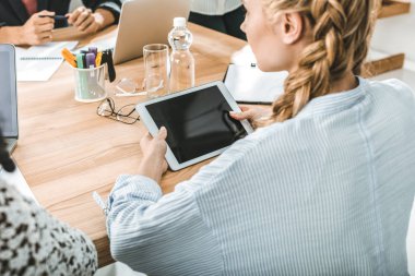 Dijital tablet meslektaşları ile toplantı sırasında masada otururken holding iş kadını yan görünüm 