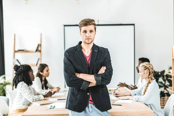 Retrato Joven Empresario Con Los Brazos Cruzados Pie Mesa Durante — Foto de Stock