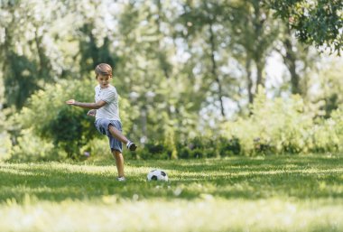 mutlu çocuk futbol topu parkta çim üzerinde oynamaktan görünümünü tam uzunlukta