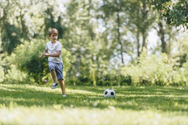 çimenlerin üzerinde çalışan ve futbol topu parkta oynarken şirin küçük çocuk