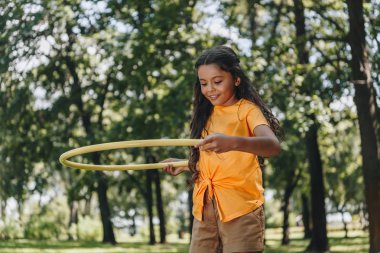 beautiful happy child playing with hula hoop in park  clipart