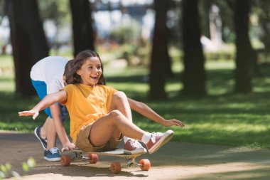 adorable happy kids having fun with longboard in park  clipart