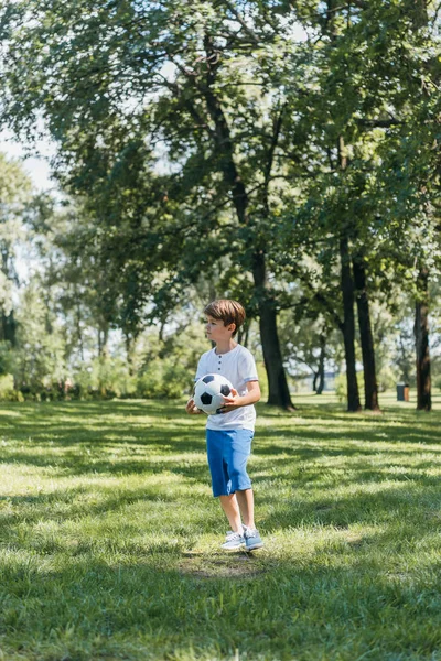 かわいい男の子サッカー ボールを押しながら公園に目をそむける  — 無料ストックフォト