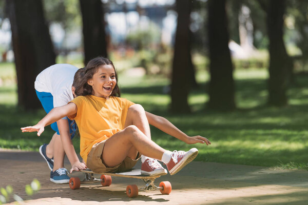 adorable happy kids having fun with longboard in park 