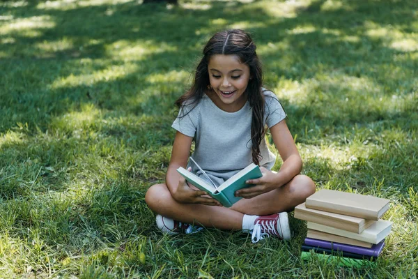 Bedårande Lyckligt Barn Sitter Gräset Och Läsa Bok Parken — Stockfoto