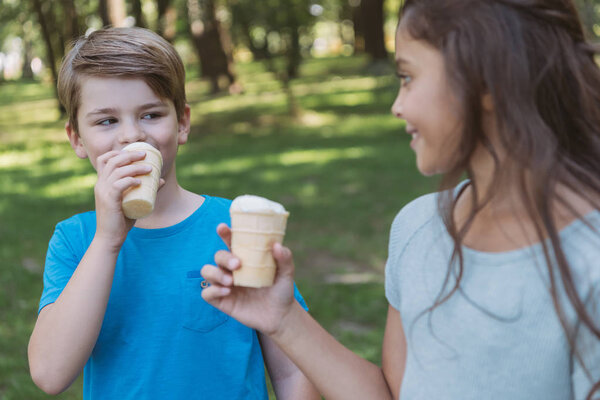 cute smiling children eating ice cream in park