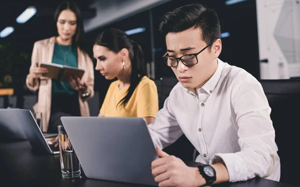 Ung Asiatisk Affärsman Använder Laptop Medan Två Affärskvinnor Arbetar Bakom — Stockfoto