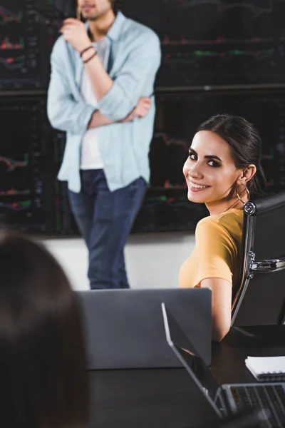 Joven Mujer Negocios Sonriente Mirando Cámara Mientras Socio Negocios Muestra — Foto de stock gratis