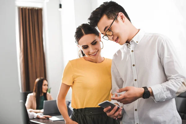 Young Asian Businessman Pointing Smartphone Screen Smiling Businesswoman Modern Office — Stock Photo, Image