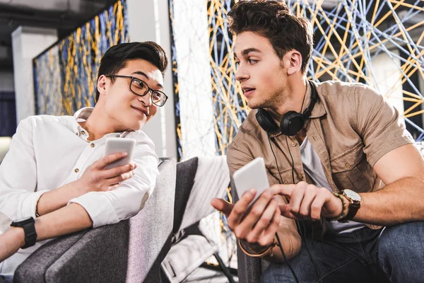 Multietniske Forretningsmenn Som Viser Smarttelefoner Til Hverandre Det Moderne Coworking – stockfoto