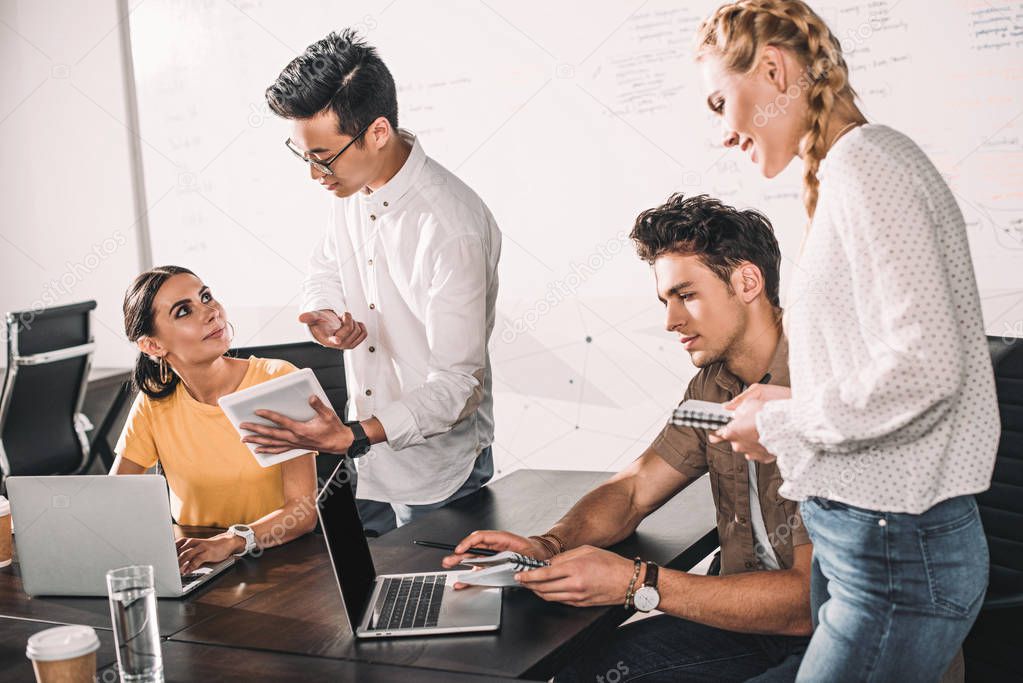 group of multiethnic business colleagues having meeting with laptops and digital tablet at modern office 