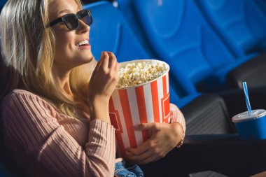 film sinemada yalnız izlerken patlamış mısır ile 3d gözlük gülümseyen kadın yan görünüm
