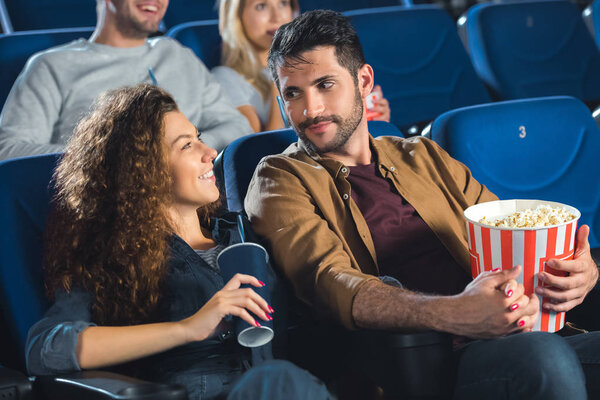 couple with popcorn watching movie together in cinema 
