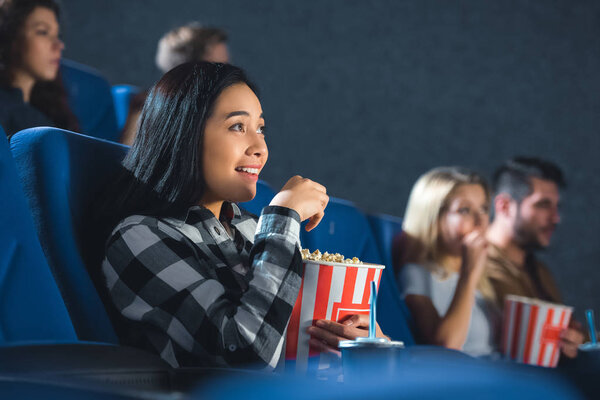 emotional asian woman with popcorn watching movie in cinema
