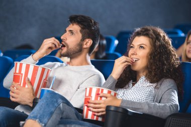 Çift birlikte sinemada film izlerken patlamış mısır yemek