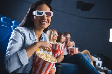 Sinemada patlamış mısır ile 3d gözlük gülümseyen Asyalı kadın seçici odak