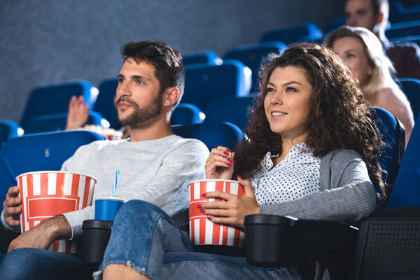 couple with popcorn and soda drink watching film together in cinema