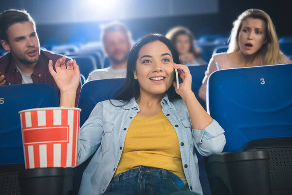 азиатка разговаривает по смартфону во время просмотра фильма в кино
 