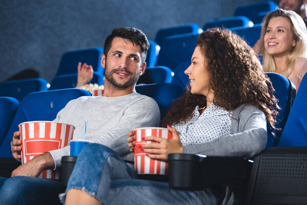 couple with popcorn and soda drink watching film together in cinema