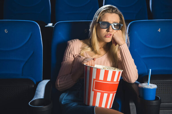 portrait of bored woman in 3d glasses with popcorn watching film alone in cinema