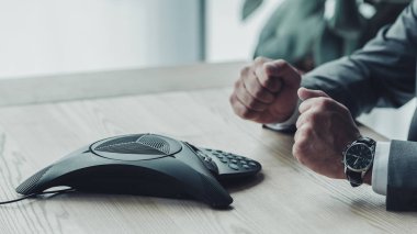 konferans telefon önünde oturan ve ofiste yumruk yapma işadamı kadeh kırpılmış