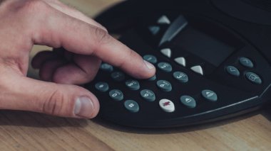 adam ahşap masanın üzerine konferans telefon düğmeye kadeh kırpılmış