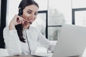 beautiful female call center worker with headphones and laptop sitting at workplace