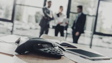 Konferans telefonunun modern ofisindeki arka plan bulanık iş kişilerle yakın çekim vurdu