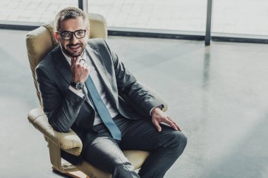Lüks koltuk modern ofisinde oturup..... yakışıklı gülümseyen iş adamı yüksek açılı görünüş