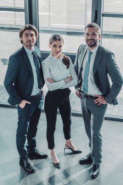 Grup modern ofis ayakta ve kameraya bakarak başarılı genç iş adamları