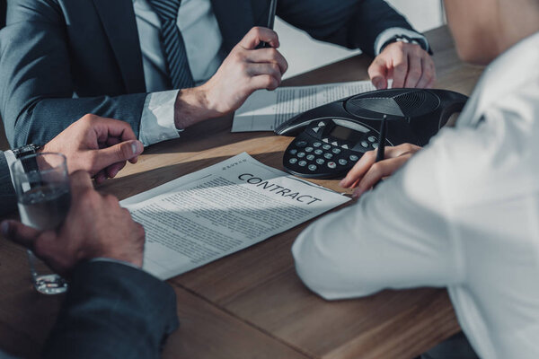 обрезанный снимок группы бизнесменов с контрактами, имеющими встречу в современном офисе
