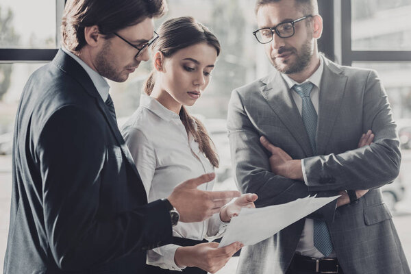 успешные молодые бизнесмены вместе обсуждают документы в офисе
